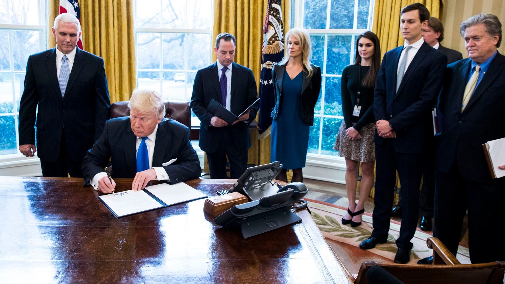 President Donald Trump signs an executive order Wednesday in the Oval Office of the White...