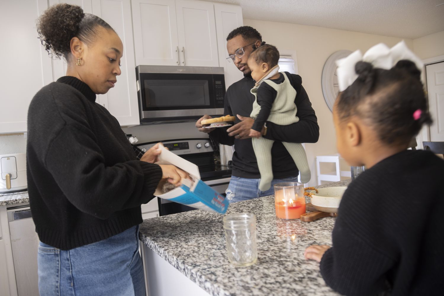 Daizha Rioland, left, and Kenneth Rioland prepare a snack for their daughters at their home...