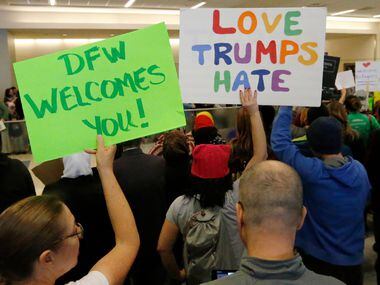 Protesters chant as they hold handmade signs at the international arrivals gate in Terminal...