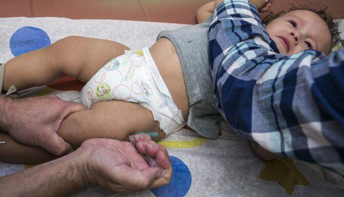 El pediatra Charles Goodman vacuna a Cameron Fierro, de 1 año, congra el sarampión, paperas...