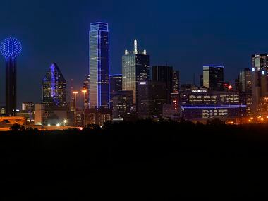 The Omni Dallas Hotel (right) reads "Back The Blue" as the skyline of Dallas is aglow in blue.