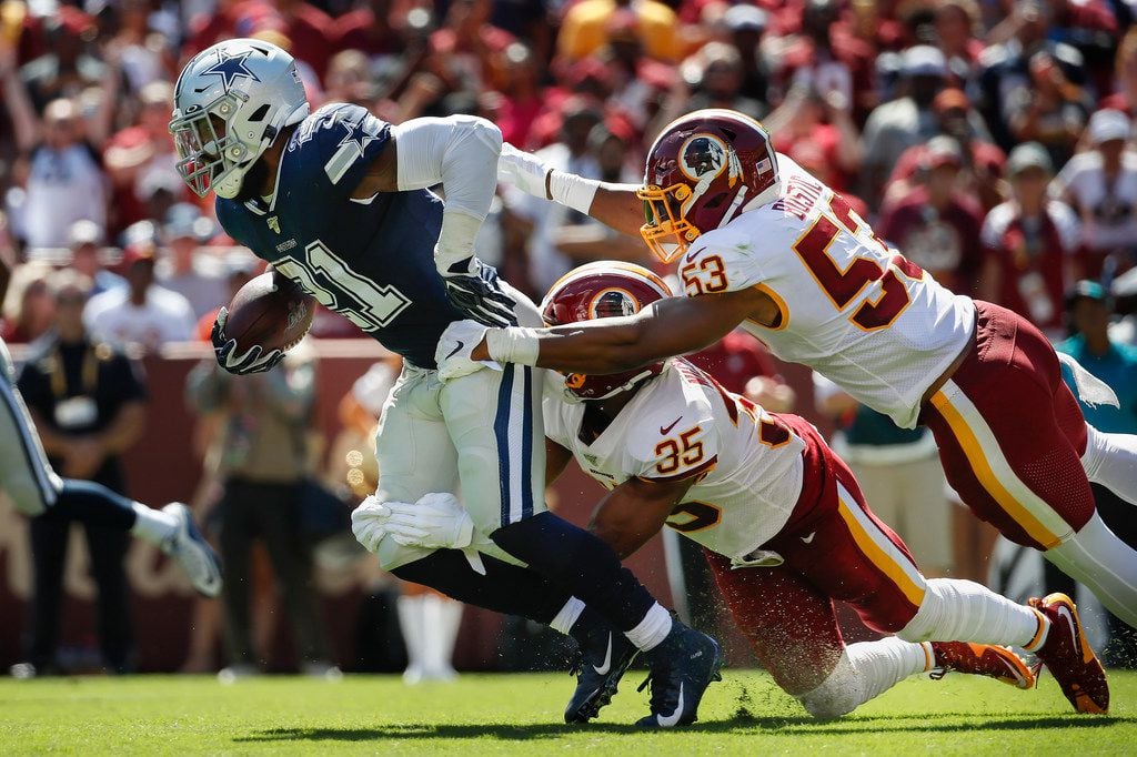 Dallas Cowboys running back Ezekiel Elliott (21) is taken down by Washington Redskins strong...