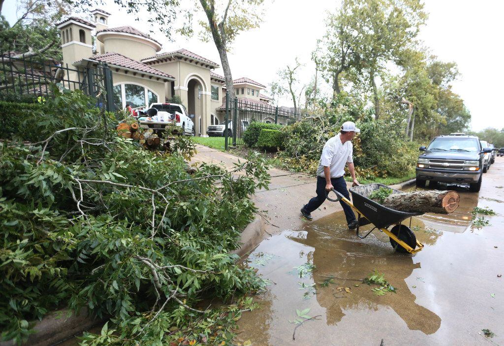 Spencer McIntyre wheels a piece of tree trunk k to the curb after a tornado spawned by Hurricane Harvey hit the Sienna Plantation subdivision southeast of Houston on Saturday, August 26, 2017.
