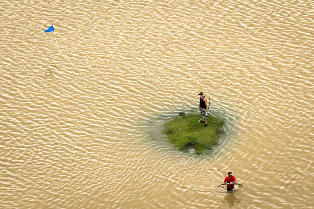 Two men carrying hunting bows find a small patch of dry ground surrounded by flood water at...