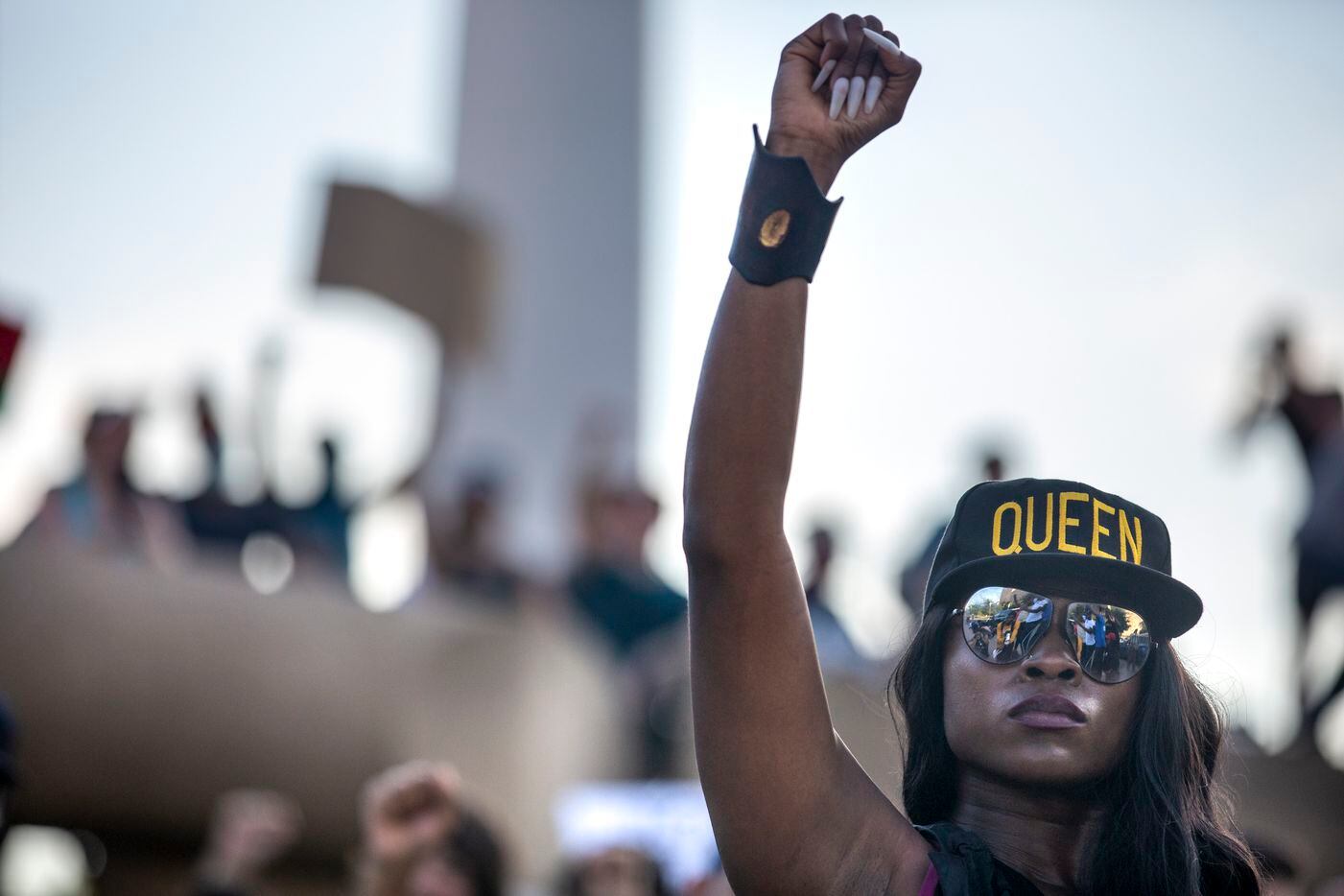 Jennifer Akabue raises her fist with other protesters as they participate in an 8-minute and...