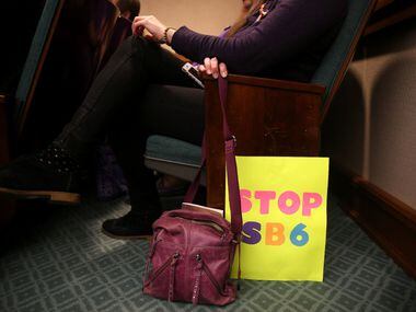 A woman waited with her sign in the overflow room as members of the Senate State Affairs...