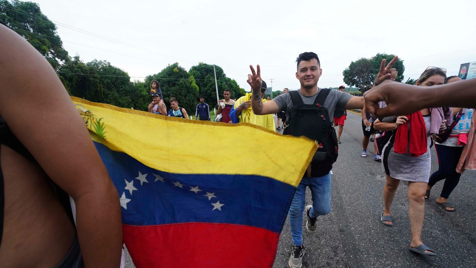 Migrantes mayormente venezolanos y centroamericanos avanzan a pie por una carretera de...