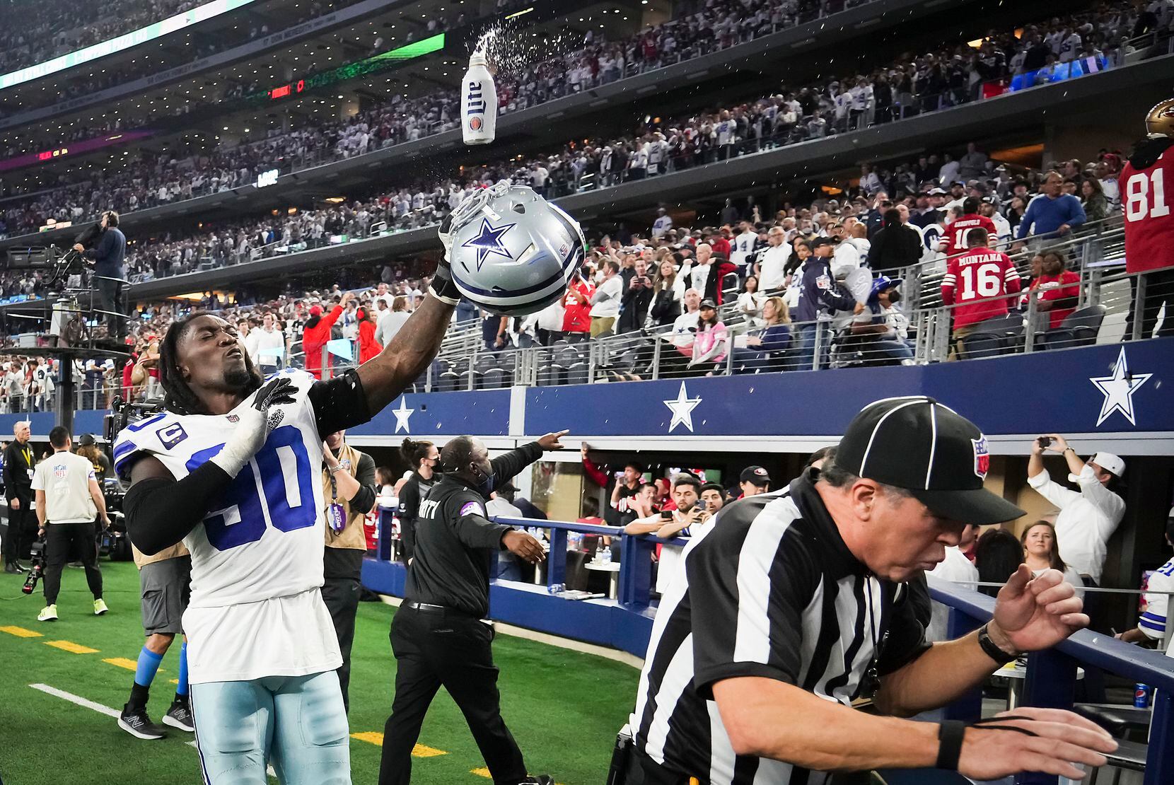 Dallas Cowboys defensive end Demarcus Lawrence (90) uses his helmet to knock away a beer...
