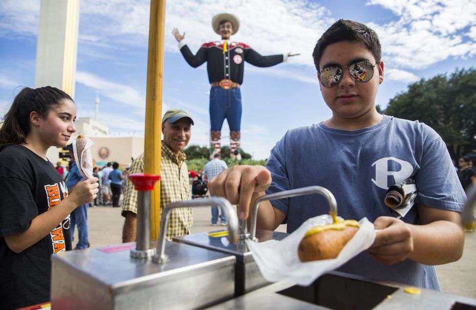 Matthew Kianpour, 15, right of Rockwall, Texas, tops his Fletcher's Corny Dog with mustard...