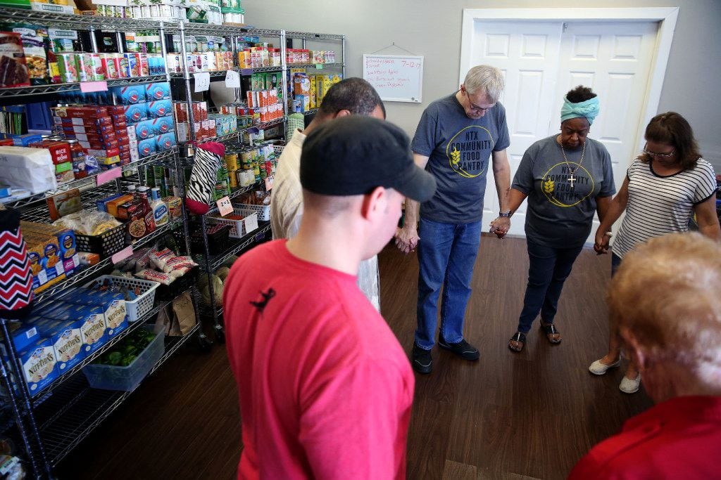 Volunteers at the NTX Community Food Pantry pray before handing out food to clients at the...