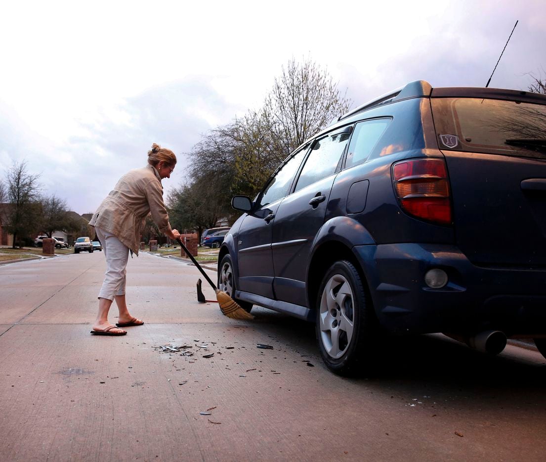 Monica Perez of McKinney sweeps up broken pieces of plastic from the wind guard that was...