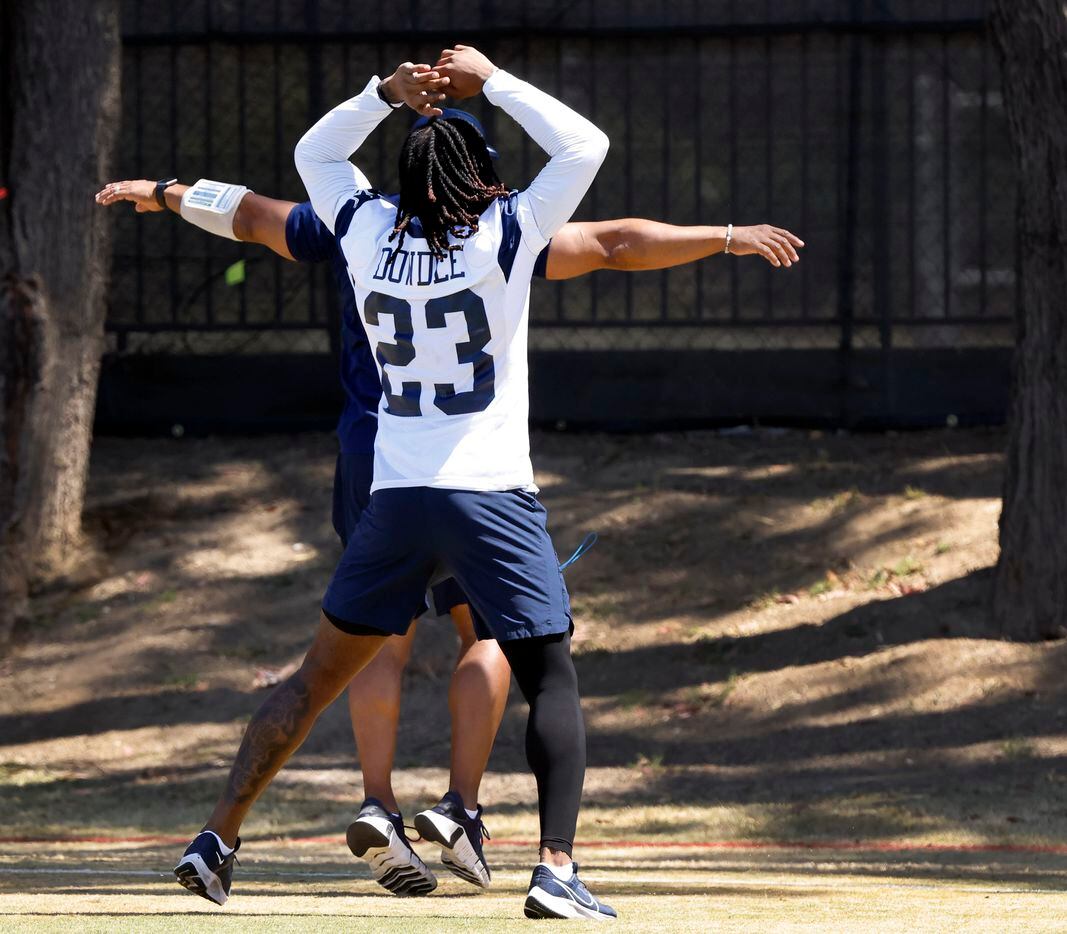 Dallas Cowboys running back Rico Dowdle (23) warms up with a strength coach during training...