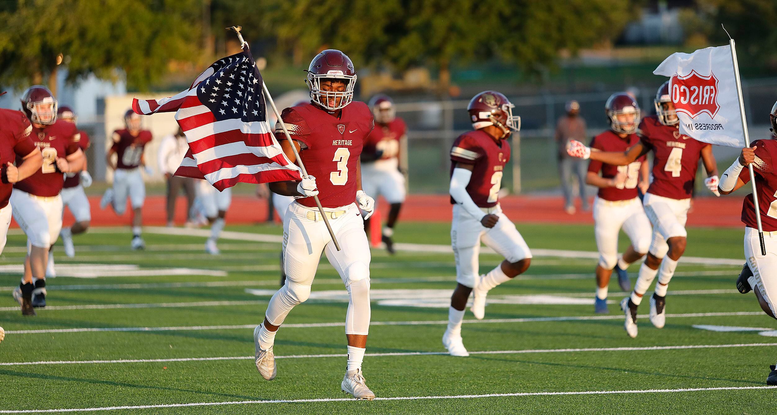 Heritage High School wide receiver Jordan Gregory (3) carries the United States flag as the...