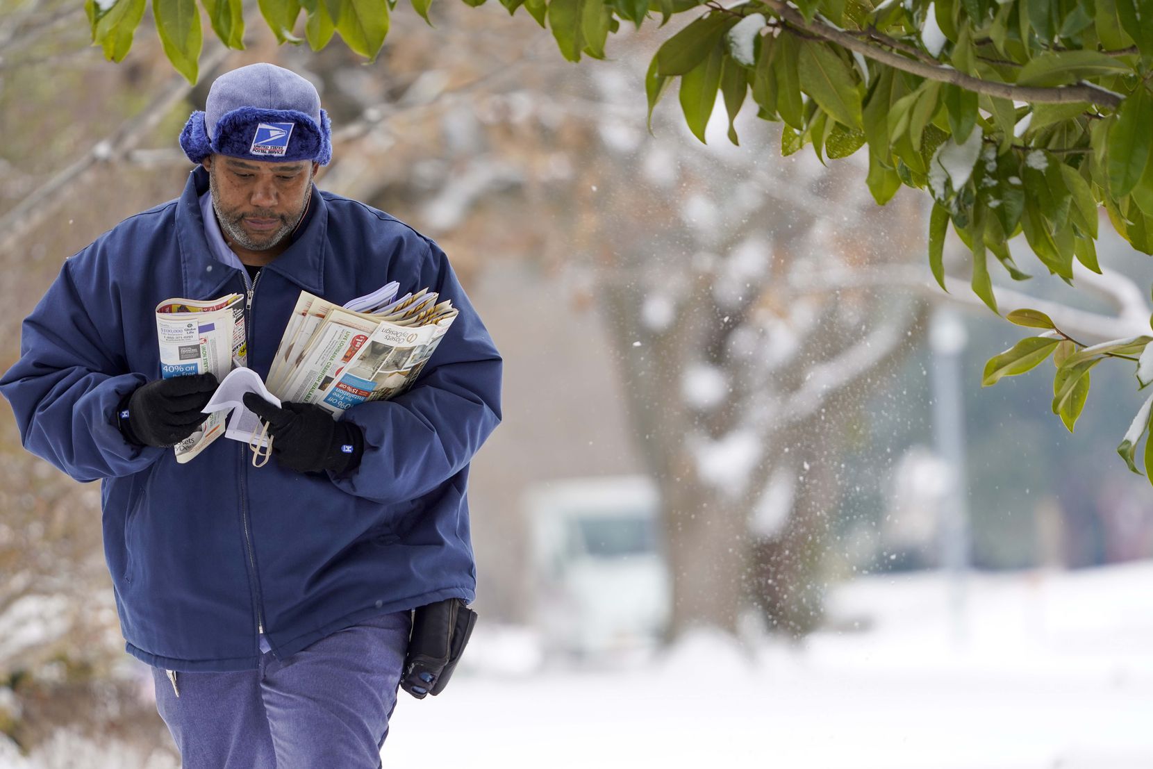 USPS mail carrier RayShawn Riley delivers mail to a snow covered neighborhood after a second...