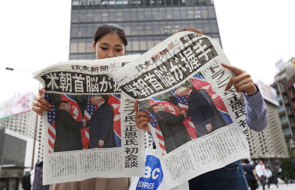 Pedestrians read extra edition newspapers reporting the summit meeting between US President...