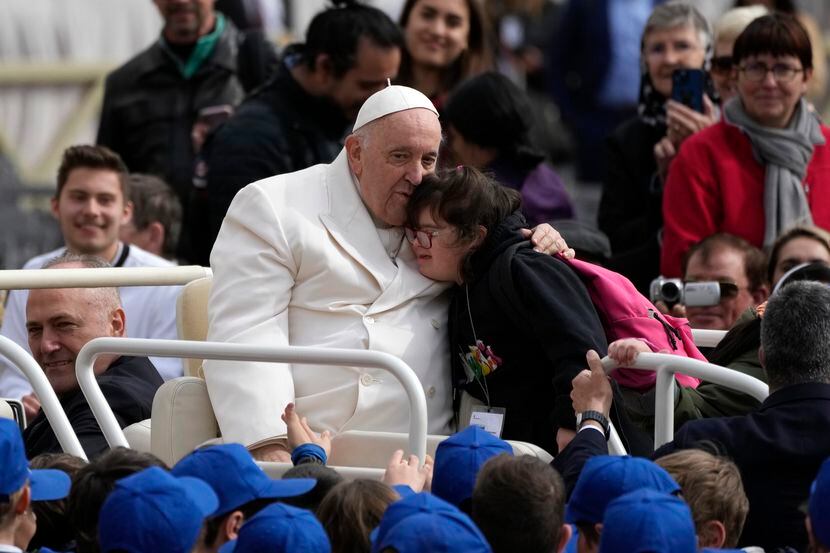 El papa Francisco abraza a una niña al finalizar su audiencia general semanal en la Plaza de...