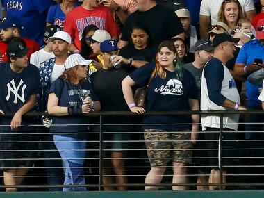 A Texas Rangers fan (center with blue hat) takes a drink after catching New York Yankees...
