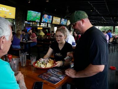 Kaitlin Brooks (center) serves Heath Bullard (left) and Mike Sheils (right) at BoomerJack's in Grapevine.