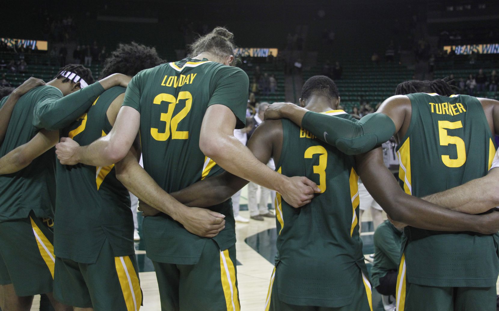 Baylor players and coaches gather at mid court for a post-game prayer following their win...