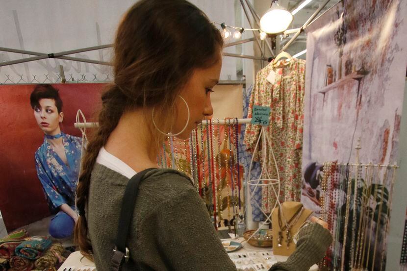 A shopper checks out the jewelry at a vendor's booth.