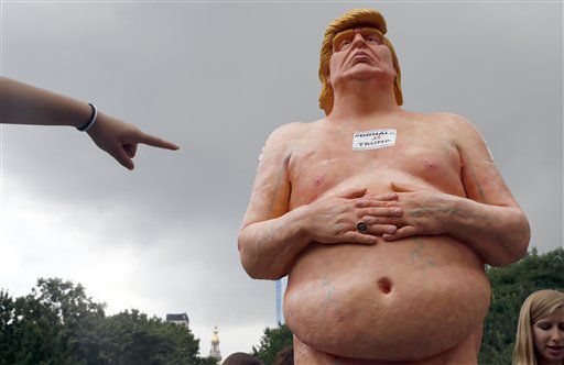 Una mujer señala una estatua del candidato presidencial republicano Donald Trump desnudo, el...