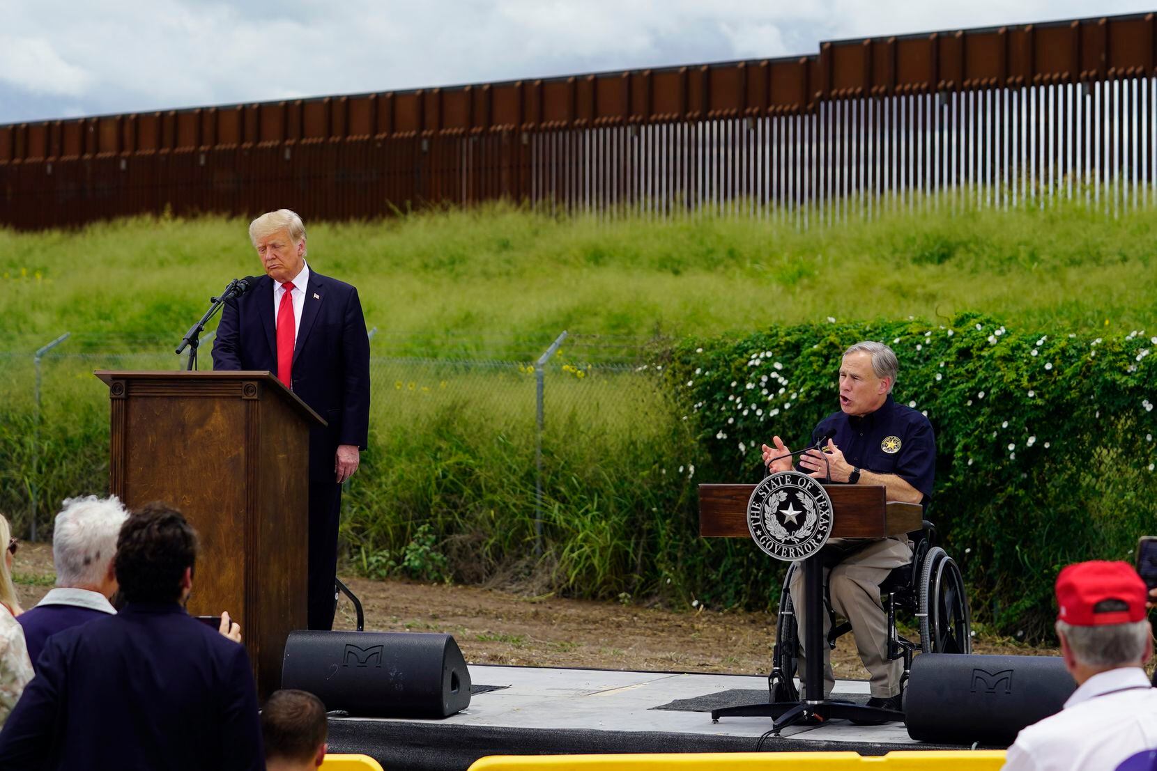 Former President Donald Trump and Texas Gov. Greg Abbott, right, visit an unfinished section...