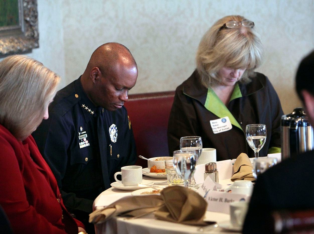 Dallas Police Chief David Brown and Dallas City Manager Mary Suhm (right) bow their heads in...