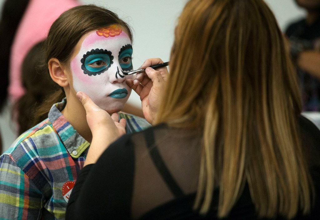 Tiffany Mahan of Dallas, 10, left, has her face painted by Margarita Barrantes of Dallas during Latino Cultural Center's Dia de los Muertos celebration.
