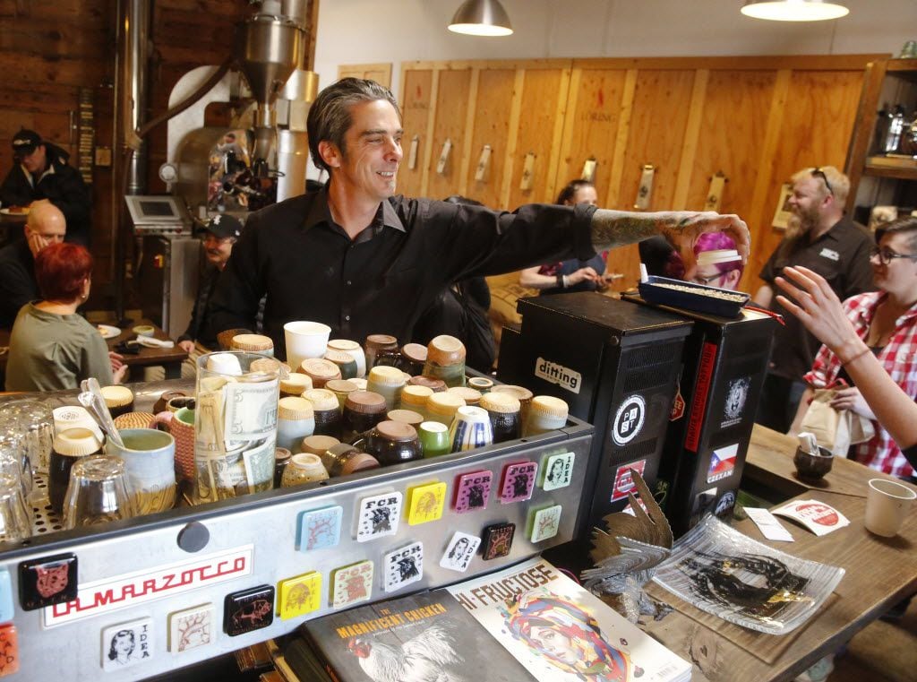 Michael Wyatt, center in black, owner of Full City Rooster, hands a coffee cup lid to a...