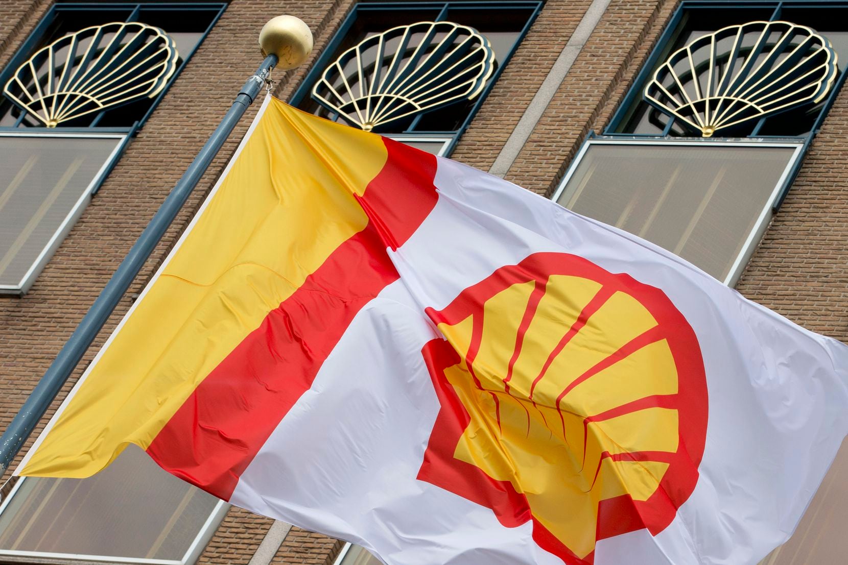 A flag bearing the company logo of Royal Dutch Shell, an Anglo-Dutch oil and gas company, flies outside the head office in The Hague, Netherlands. 
