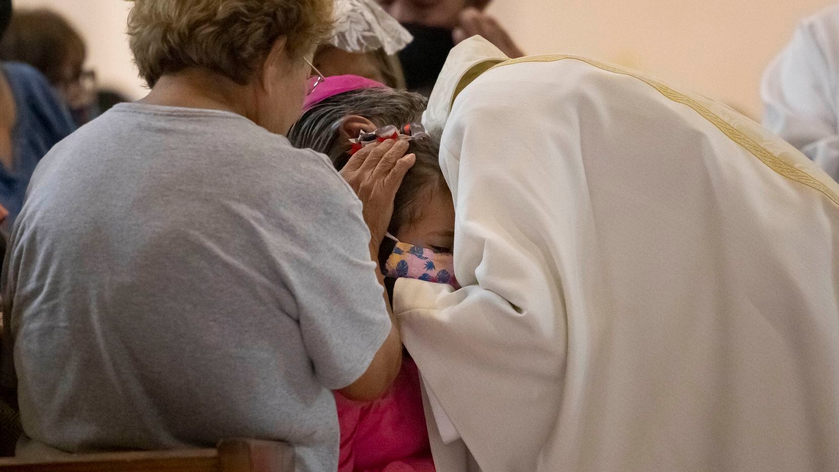 El arzobispo Gustavo García-Siller reza sobre una niña durante una misa de emergencia...