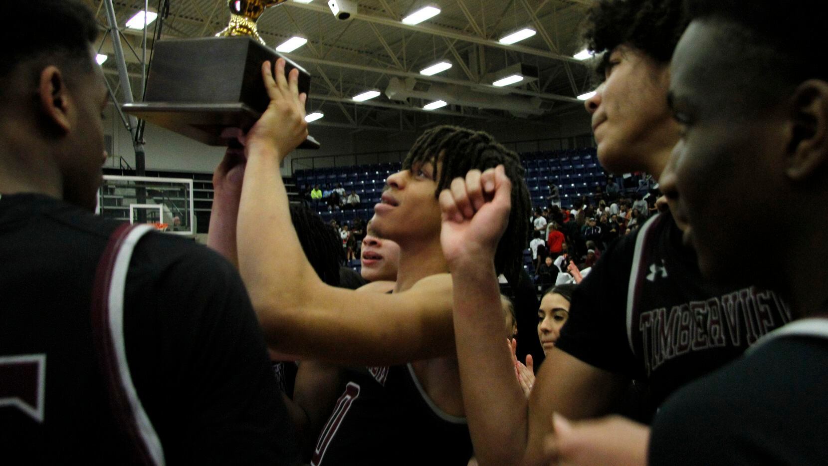 Mansfield Timberview players gather at mid-court as Joey Madimba raises the trophy after Timberview beat Mansfield Legacy 41-40 in overtime in Tuesday's Class 5A Region I quarterfinal.