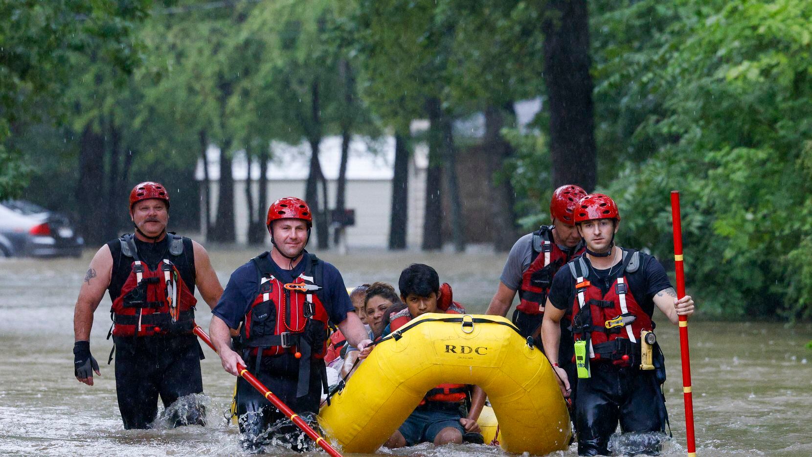 Members of the Balch Springs Fire Department bring a family of four by boat to higher ground...