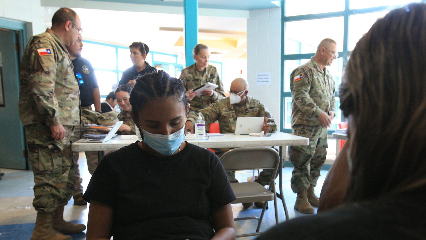 Daniela Linares waits for her turn to provide information to a Texas National Guard officer...
