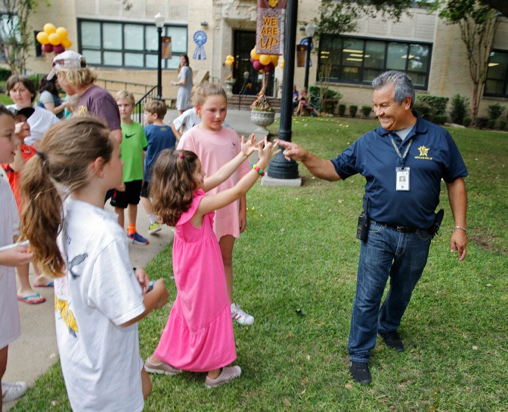 Jesus Gonzalez, a janitor for University Park Elementary School, is greeted by Anna Bel, 6,...