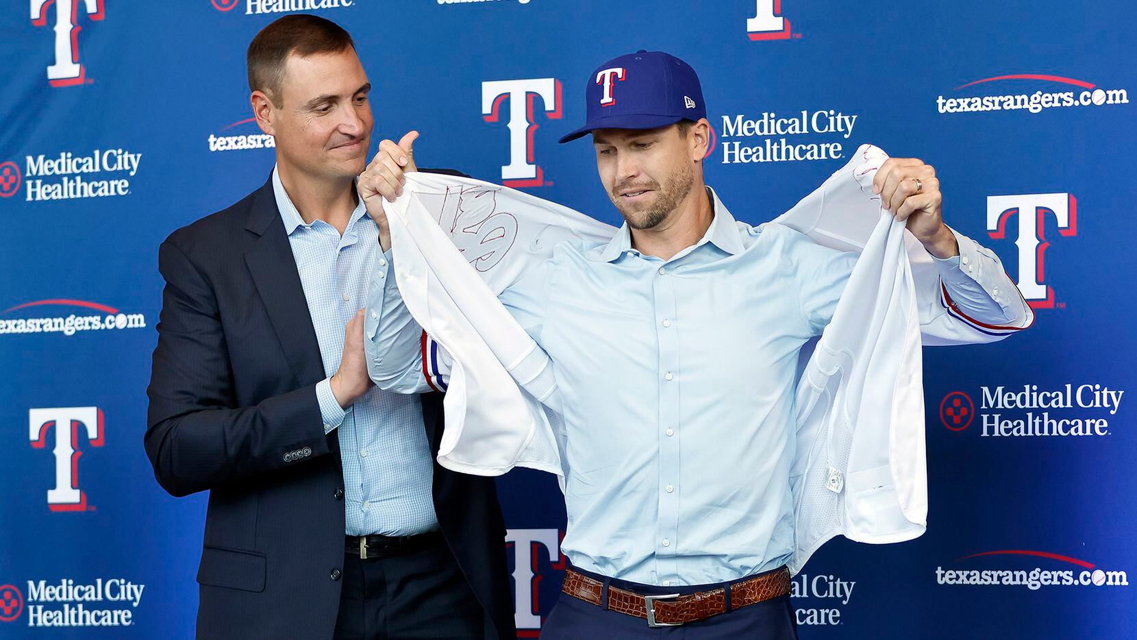 New Texas Rangers starting pitcher Jacob deGrom tries on his new jersey with the assistance...