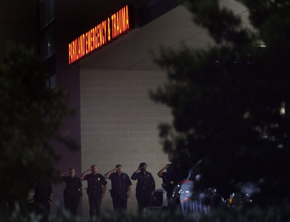 Dallas police officers stood in salute as fallen officers were transported into UT Southwestern vans through a secure entrance at Parkland Memorial Hospital in Dallas early Friday. 
