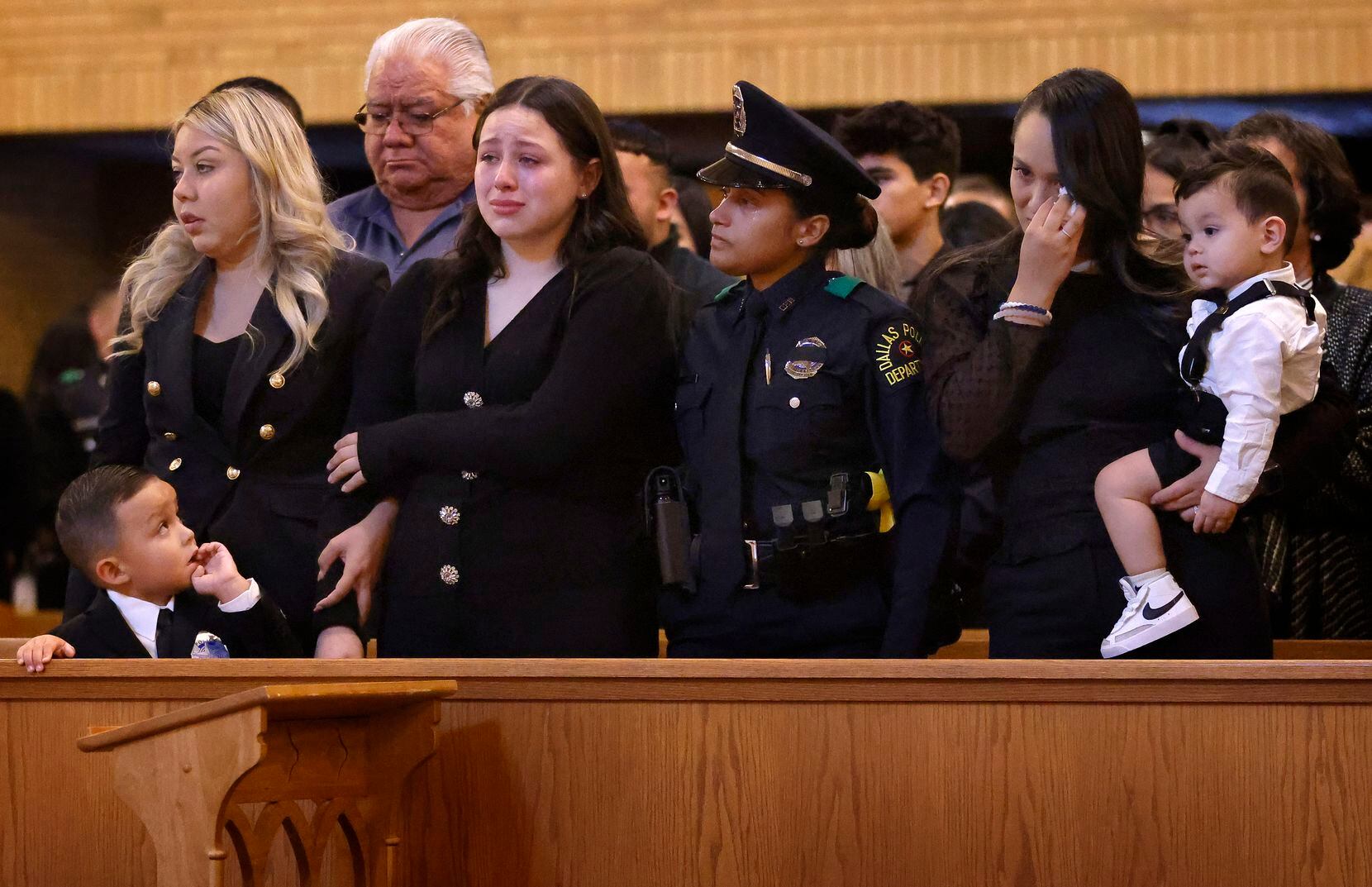 Mia Arellano (center) is comforted by a Dallas Police Officer during the funeral Mass for...
