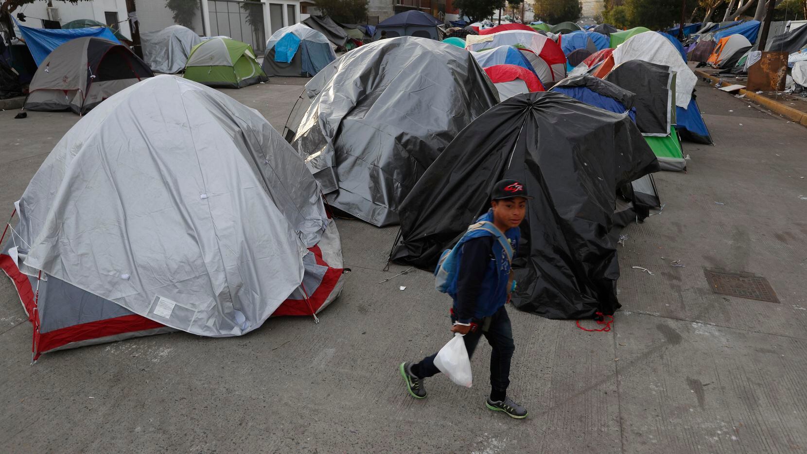 Una persona camina frente a un campamento improvisado para albergar a migrantes de...