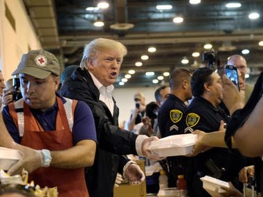 President Donald Trump passes out food and meets people impacted by Hurricane Harvey during a visit to Houston's NRG Center Saturday. It was his second trip to Texas in a week.