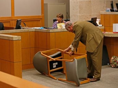 Defense attorney Andrew Farkas (right) rearranges two chairs on their side while defendant...