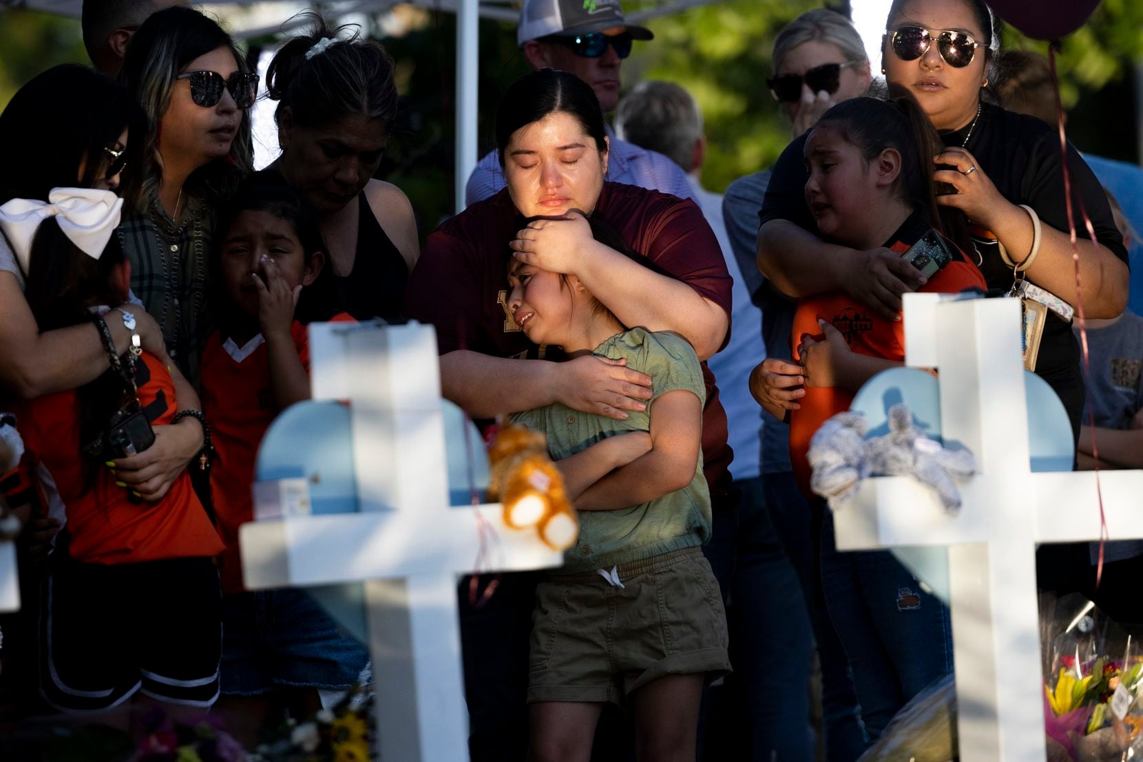 Geneva Uriegas (center) holds her daughter Gabriela while they stand in front of the cross ...