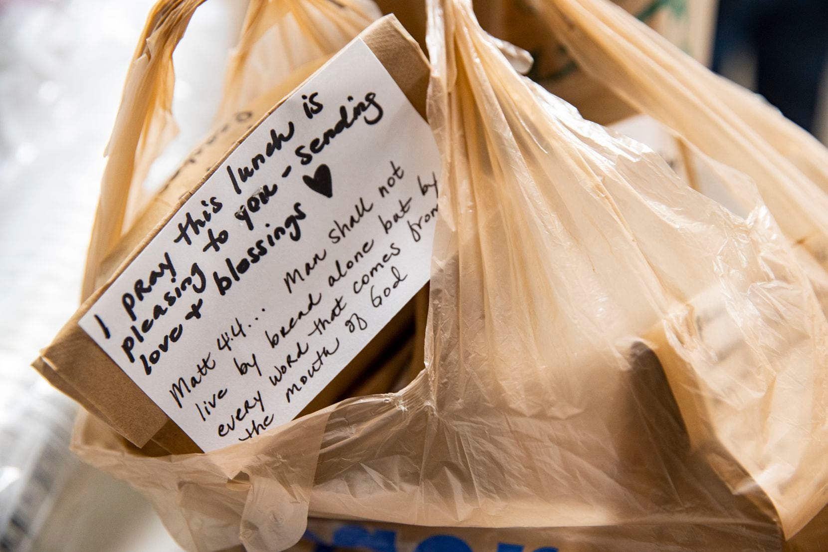 Hand-written notes are placed in the bags of those receiving meals at Cornerstone.