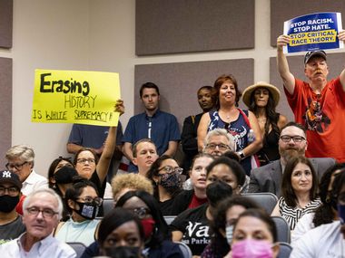 A community member holds a "Erasing history is white supremacy" sign as someone holds a "Stop critical race theory" sign on Tuesday, June 22, 2021, during the Fort Worth ISD board meeting in Fort Worth. (Juan Figueroa/The Dallas Morning News)