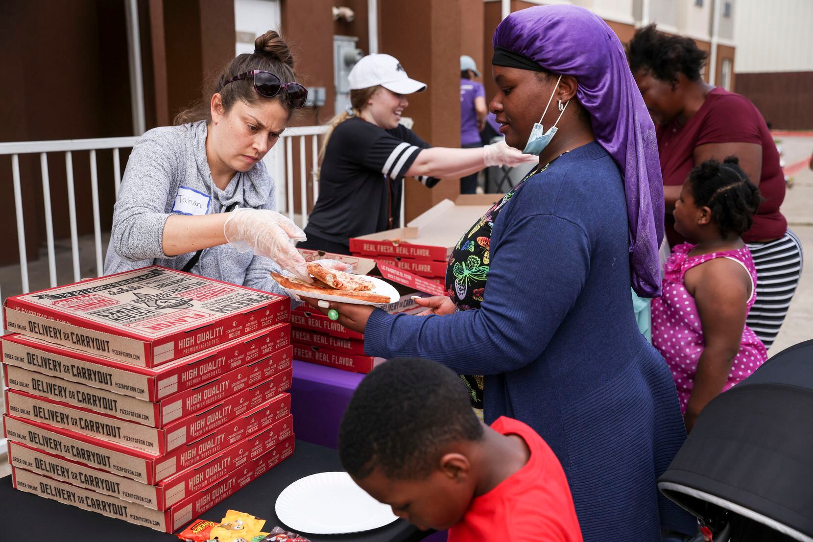 Na'Tiffany Thomas receives a piece of pizza from volunteer Tahani Abu-Shamala at Family...