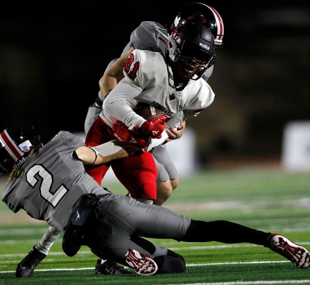 Frisco Liberty receiver Chris Johnson (21), center, is wrapped up by Lucas Lovejoy defenders...