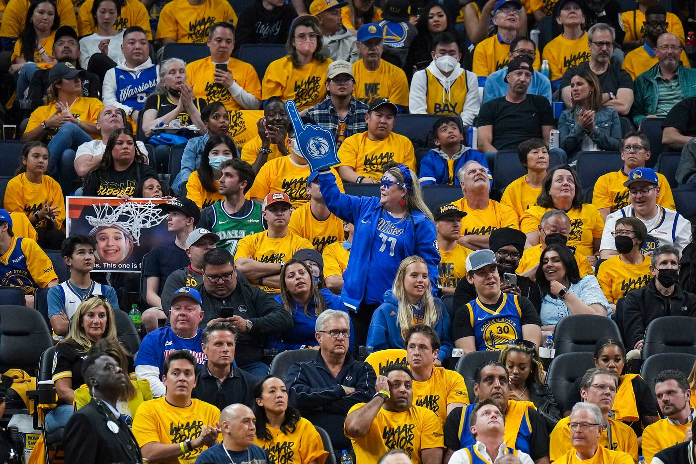 A Dallas Mavericks fan celebrates a basket while surrounded by Golden State Warriors fans...