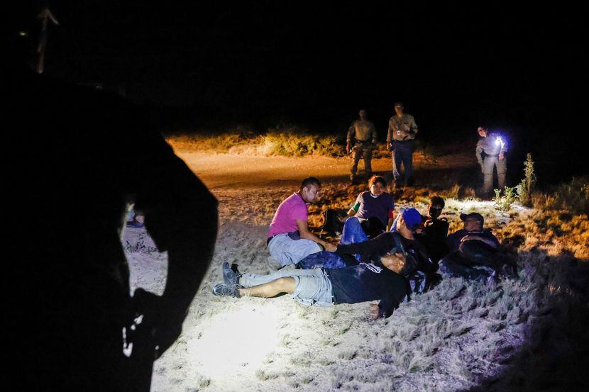 A group of migrants, five men and a 17-year-old girl, sat on the ground waiting to be...
