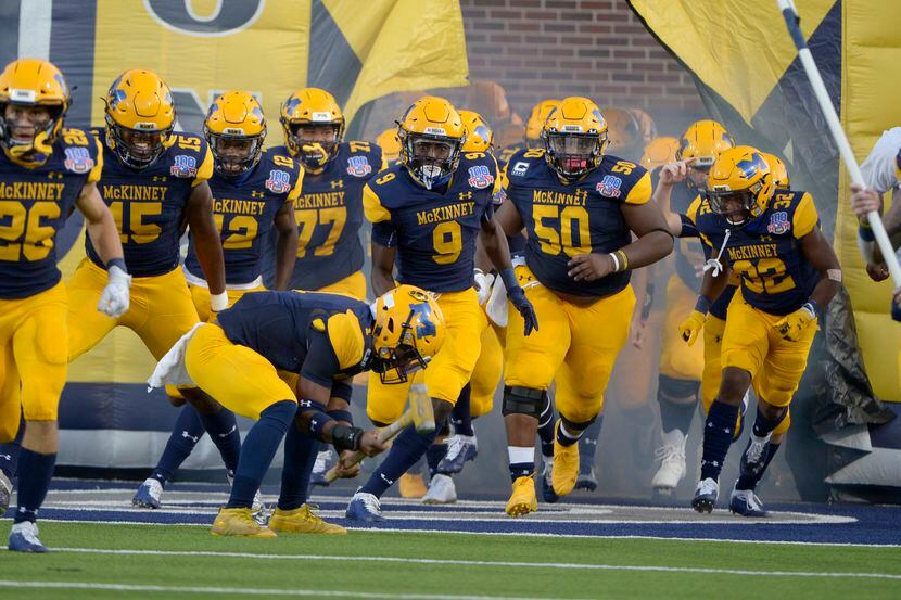 McKinney players run onto the field before a high school football game between Plano and...
