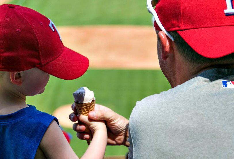 A father and son share ice cream as they watch the Texas Rangers at Globe Life Park in...